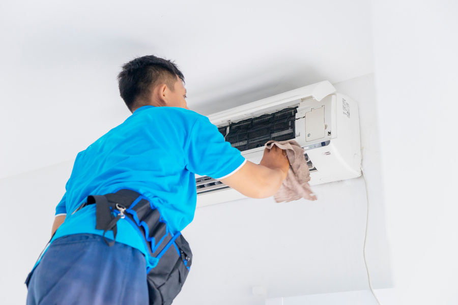 Male Technician Wiping Air Conditioner with a Cloth